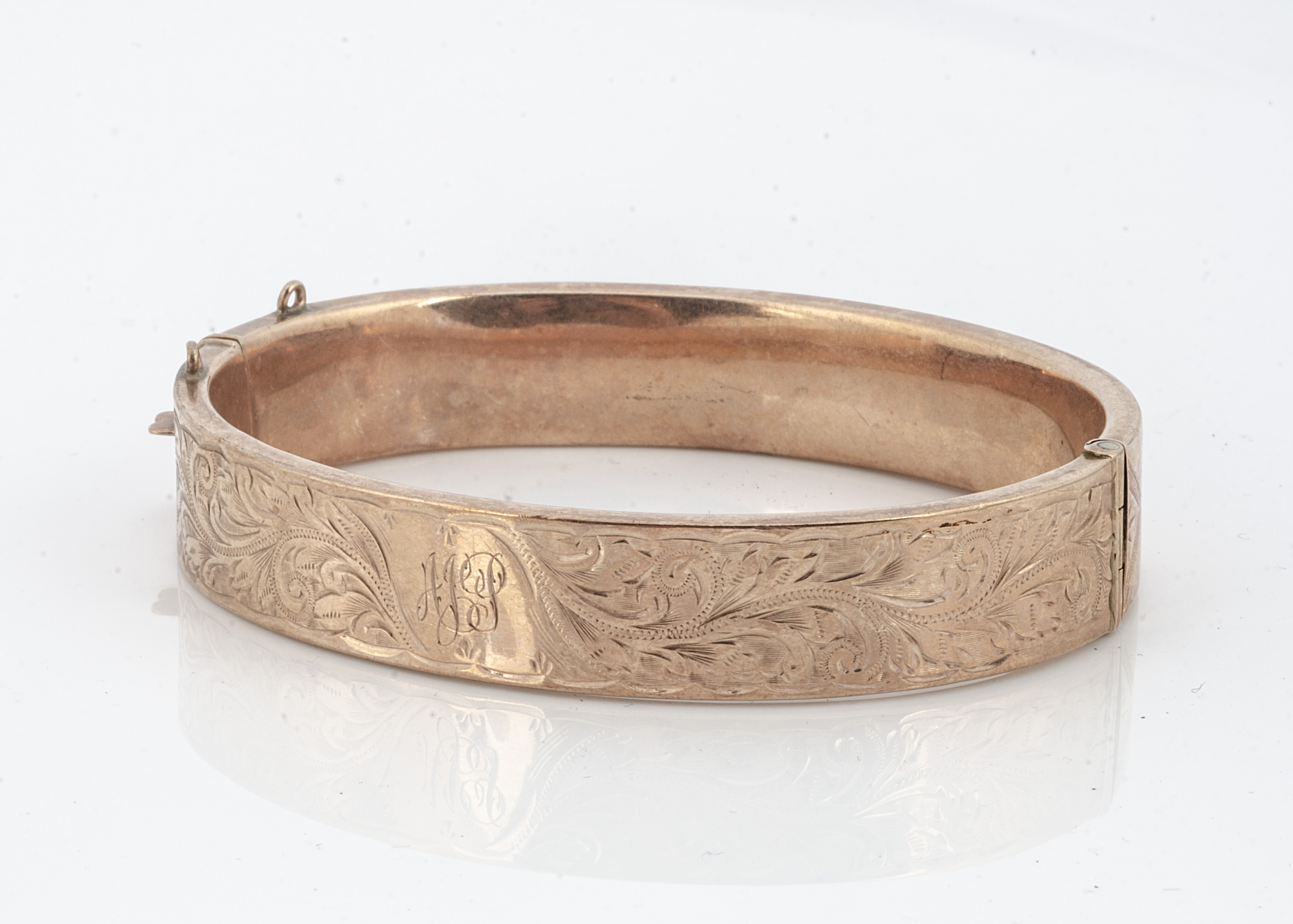 A 9ct gold hinged bangle, with engraved floral decoration, 6cm x 5.2cm internal measurement, 17.2g