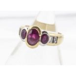 An 18ct gold three stone ruby and diamond set dress ring, the three oval cut rubies in rubbed over