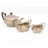 A George V silver three piece tea set by James Deakin & Sons, squat form with feathered and acanthus