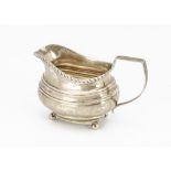 A George III period silver milk jug, helmet shaped on four bun feet, dented, marks worn, 3.64 ozt