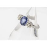 A sapphire and diamond three stone platinum dress ring, the oval mixed cut blue sapphire in claw