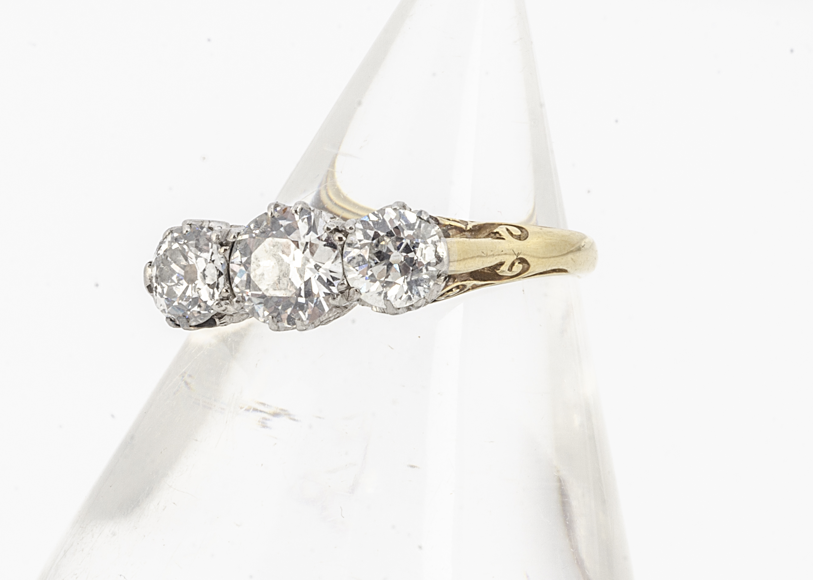 A three stone diamond ring, the old cuts in claw setting on a yellow metal shank marked PLAT and
