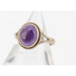 An amethyst cabochon 9ct gold dress ring, the mauve stone with rope twist setting, yellow gold