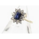 A 9ct gold sapphire and diamond cluster ring, the step cut claw set sapphire surrounded by