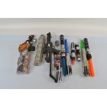 A collection of assorted Star Wars lightsaber and blaster toys, including a Darth Vader