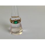 An 18ct gold emerald and diamond three stone dress ring, the circular mixed cut emeralds in claw