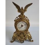 A lacquered brass mantel clock, surmounted by an eagle, 34cm high with quartz movement