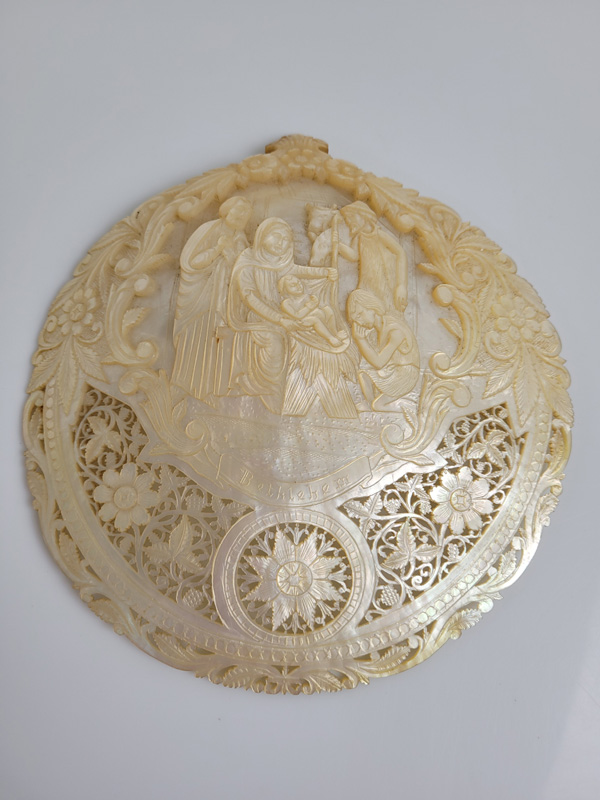 A mother of pearl pilgrim shell, with carved and pierced decoration depicting the Nativity with