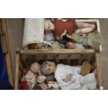 A Lloyd Loom type dolls' cot, 65cm long; a wooden rocking cradle and a quantity of damaged dolls,