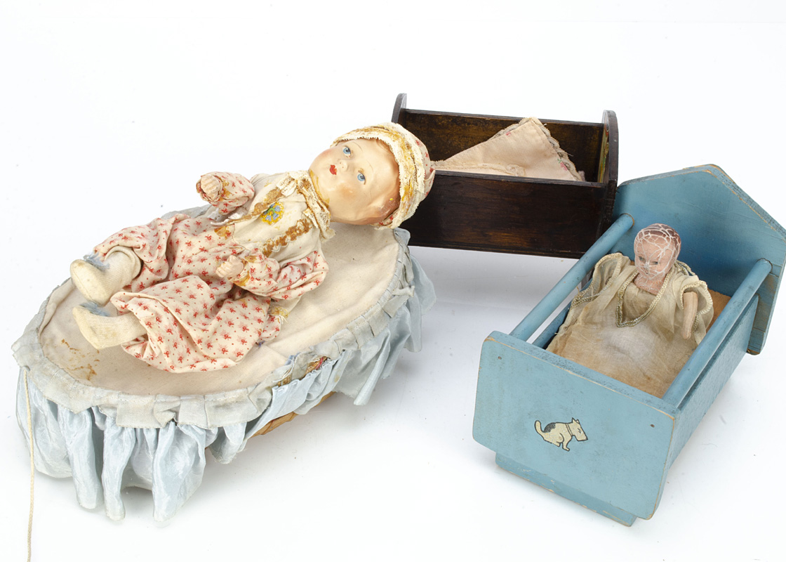 A German pull-a-long crying and wriggling baby in cot, with composition head, hands and feet, blue