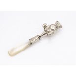 An English silver teddy bear teething rattle, hallmarked Birmingham 1910, a seated bear on top of