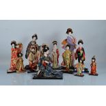 Eleven Japanese gofun women, in traditional dress on stands, one seated playing stringed