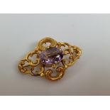 A 19th Century gilt metal and amethyst oval pierced work brooch, centred with mixed cut within a