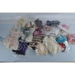 A quantity of dolls dresses and outfits, various sizes including a crimson skirt with cream
