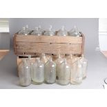 Two vintage crates of glass bottles, the pine boxes each supporting ten clear heavy bottles, some