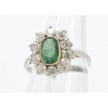 An emerald and diamond 18ct gold cluster ring, the oval mixed cut emerald surrounded by brilliant