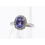 An oval tanzanite and diamond cluster ring, the central oval cluster in four claw setting surrounded