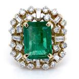 An emerald and diamond cluster ring, the Columbian emerald cut surrounded by baguette and