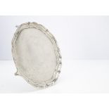 A George VI silver salver by Elkington & Co, circular with shaped rim and on four scroll supports,