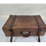 A large early 20th Century leather suitcase, with base metal fixtures and leather strap, 71cm wide x