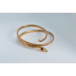 A rolled gold expandable serpentine bangle, circa 1900, with red paste set head, marked Rolled
