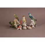 A group of porcelain and pottery birds, including a budgerigar, a finch with damaged becks, pair