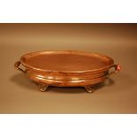 An Edwardian period copper chafing dish, oval with twin handles on four supports, 44cm, and having