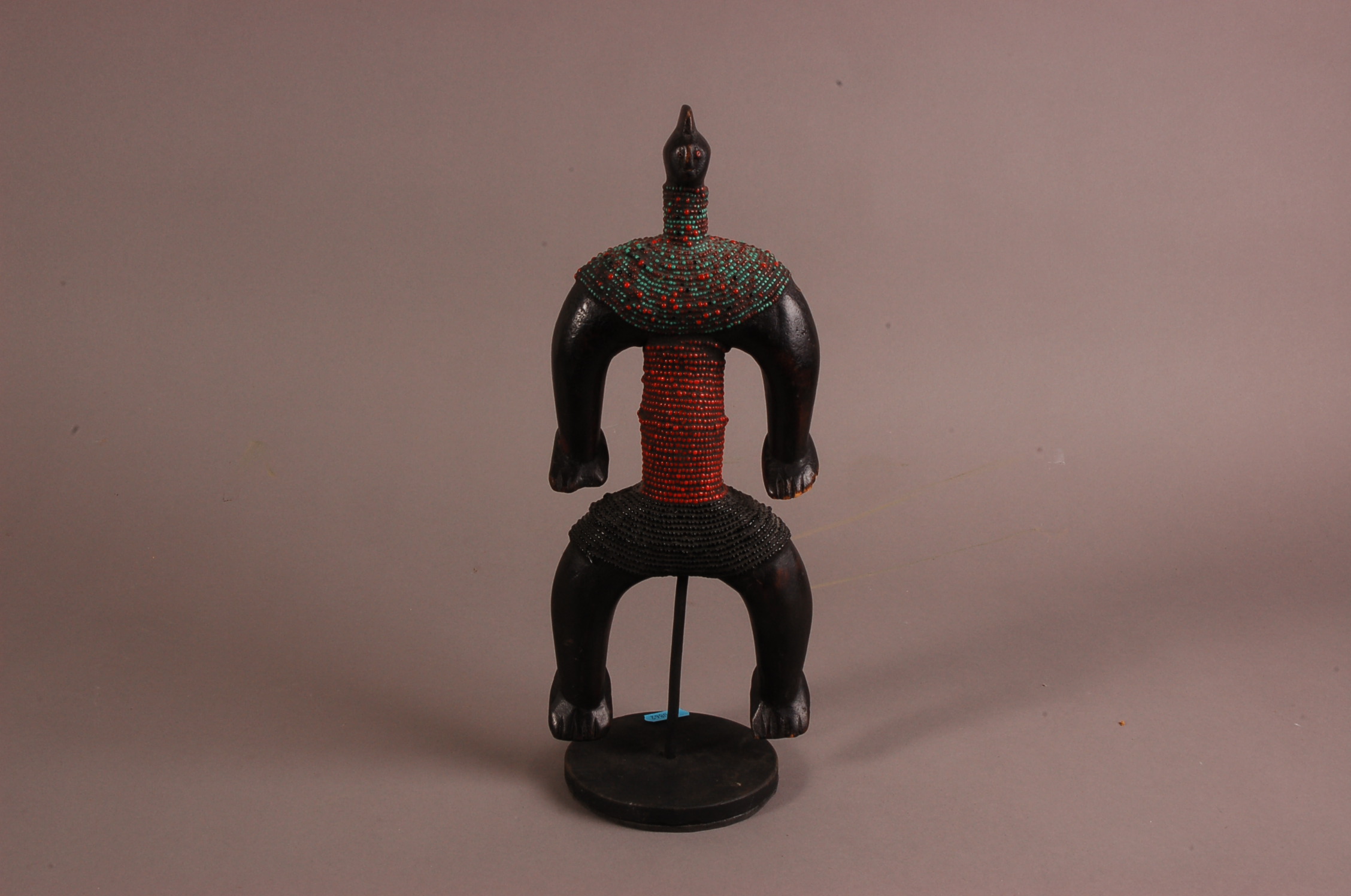 A first half 20th century African tribal wooden carving of a figure, with applied beads to torso, on