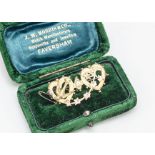 A boxed Edwardian 9ct gold double heart brooch, with swallow and ivy leaf swag design in green