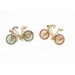 Two 18ct gold enamel and gem set bicycle brooches, with red and green enamel wheels having rough cut
