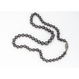 A graduated knotted strung black cultured pearl necklace, on an oval diamond platinum and gold set