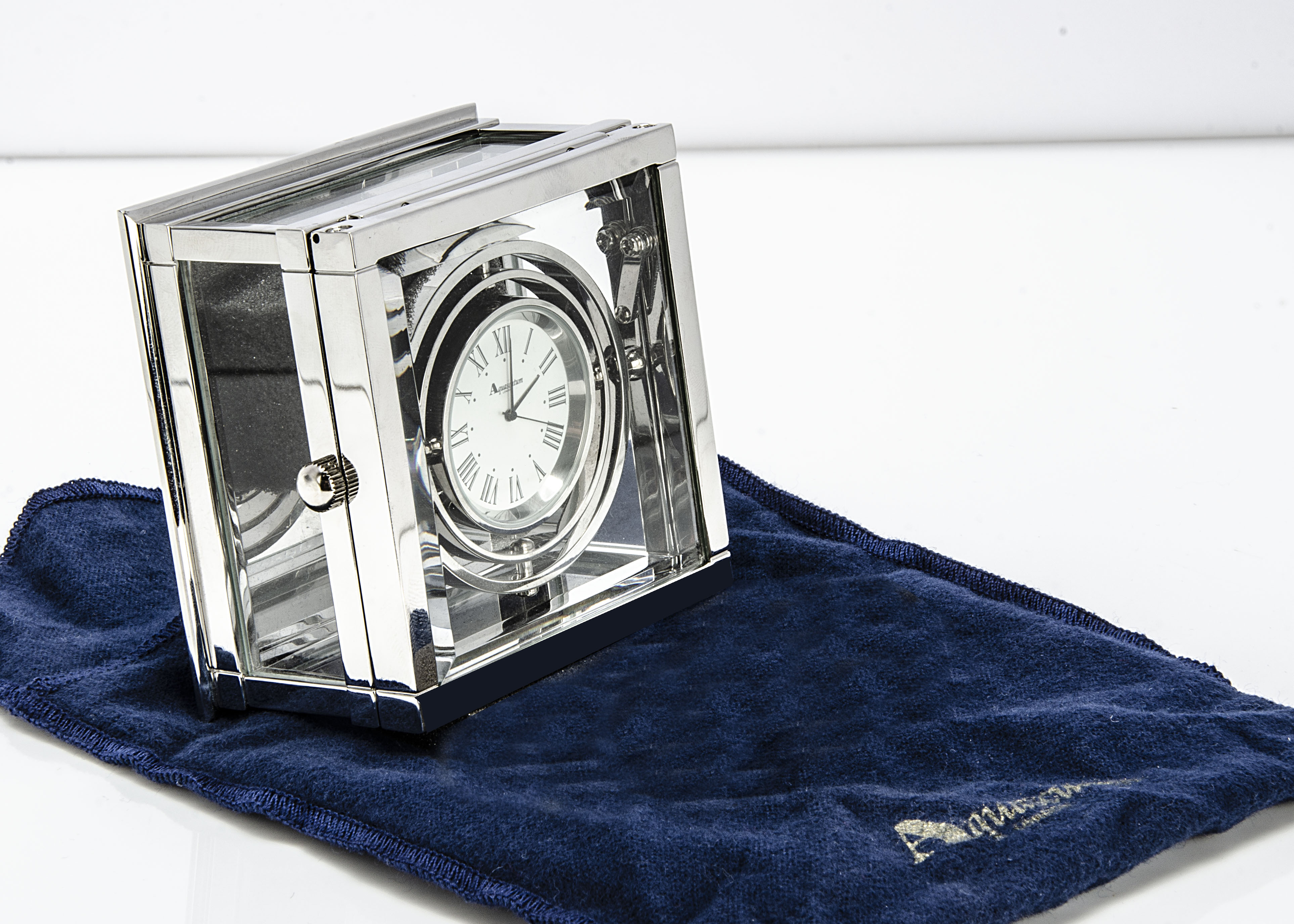 A modern silver plated desk clock from Aquascutum, square with glass panels and containing a ship'