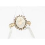 An 18ct gold opal and diamond cluster ring, the oval opal heavily af, surrounded by a bezel of small