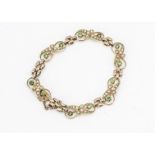 An Edwardian 15ct gold seed pearl and demantoid garnet bracelet, the knotted links with tapering