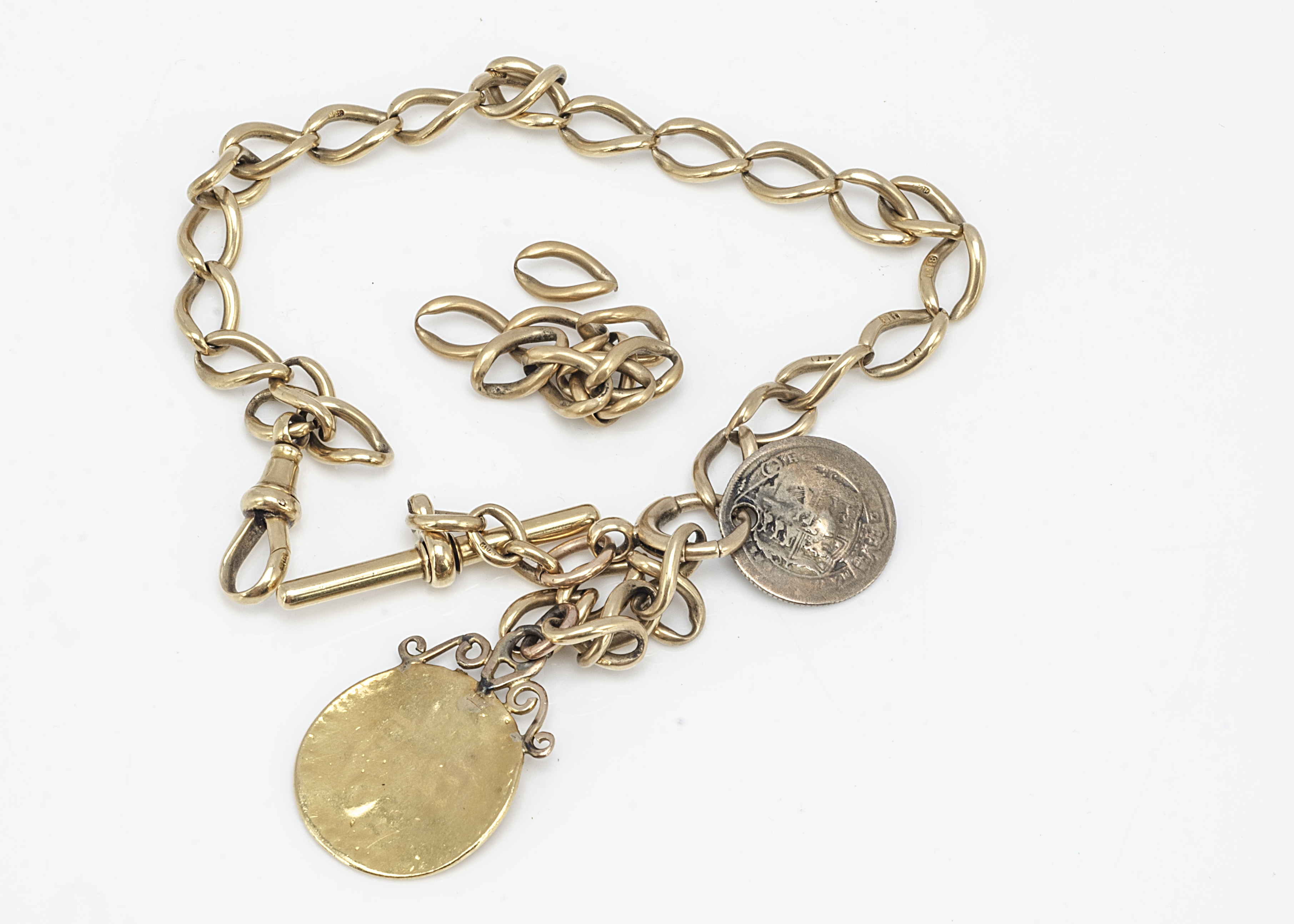 An 18ct gold curb linked watch chain, with worn spade Guinea with T bar attachment and spare