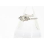 An Art Deco style platinum diamond dress ring, the round brilliant cut in eight claw setting flanked