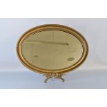 A gilt framed oval mirror, having bevelled glass and beaded moulded border. 87cm x 62cm