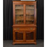 An oak Arts and Crafts glazed top bookcase, having double leaded glazed doors, two-three shelf