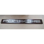 A Porsche wall mounted sign, the metal 'Porsche' lettering laid down on a wooden wall panel, letters