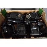 A collection of black plastic vintage telephones, including one rotary example and the other call