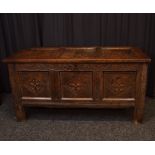 A rectangular carved oak blanket box, having inner candle box, metal ring hinges, three panel lift