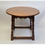 An Arts and Crafts oak circular table, having shaped apron, turned and carved legs and stretchers,
