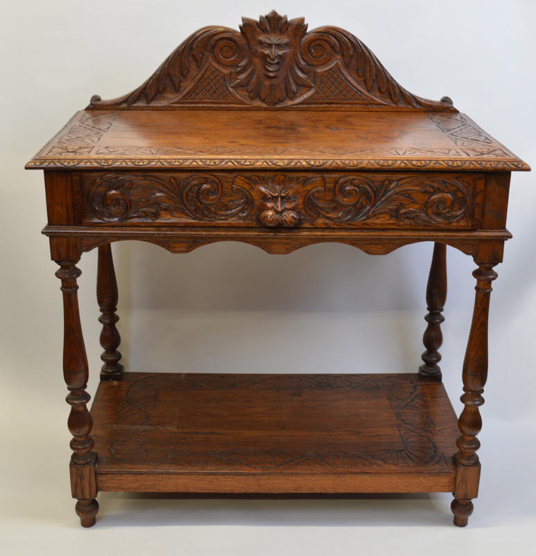 A heavily carved light oak hall table, having carved and shaped figural top rail, carved border to