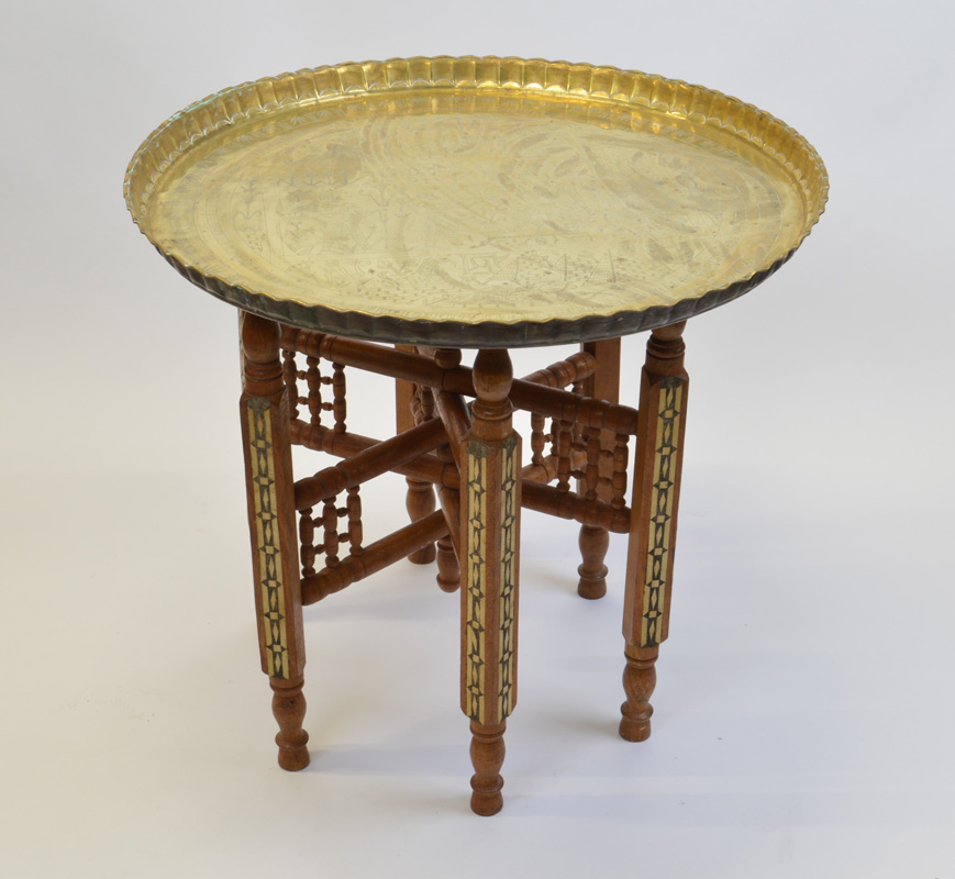 An Egyptian revival brass tray top table, with folding wooden stand with inlaid panels to the