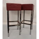 A pair of vintage stainless steel bar stools, rectangular form with red leather cushioned seats,