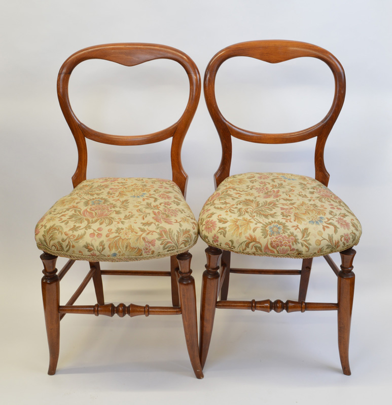 A pair of mahogany framed balloon back bedroom chairs, having shaped floral upholstered stuff over
