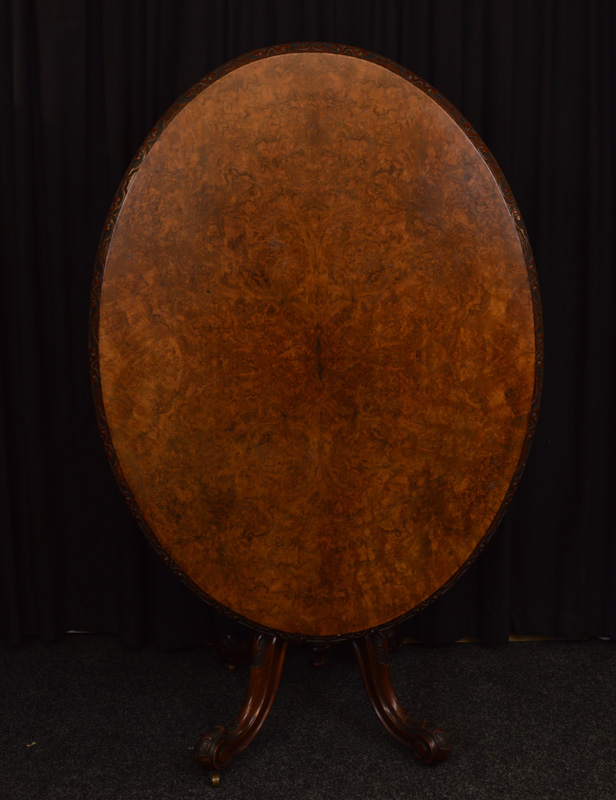 A Victorian burr walnut oval loo table, having carved scroll border on vase support, four carved