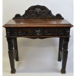 A heavily carved oak Green Man table, having figural carving to shaped back over rectangular top