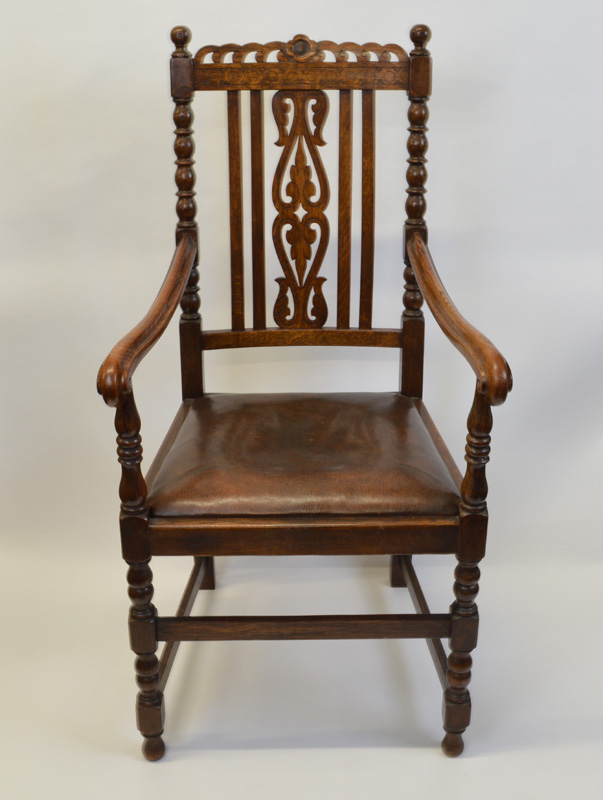 An oak framed throne armchair, having leather pad seat, moulded arm supports, carved vase back