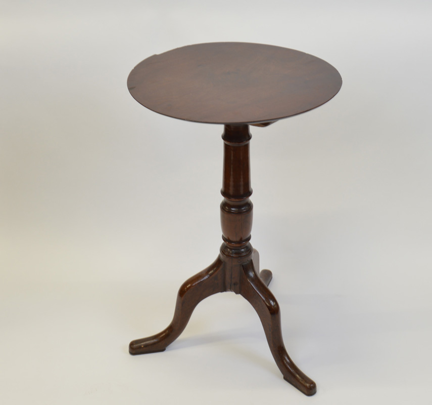 A George III oak circular snap top tripod table, having four plank top, vase support, shaped,
